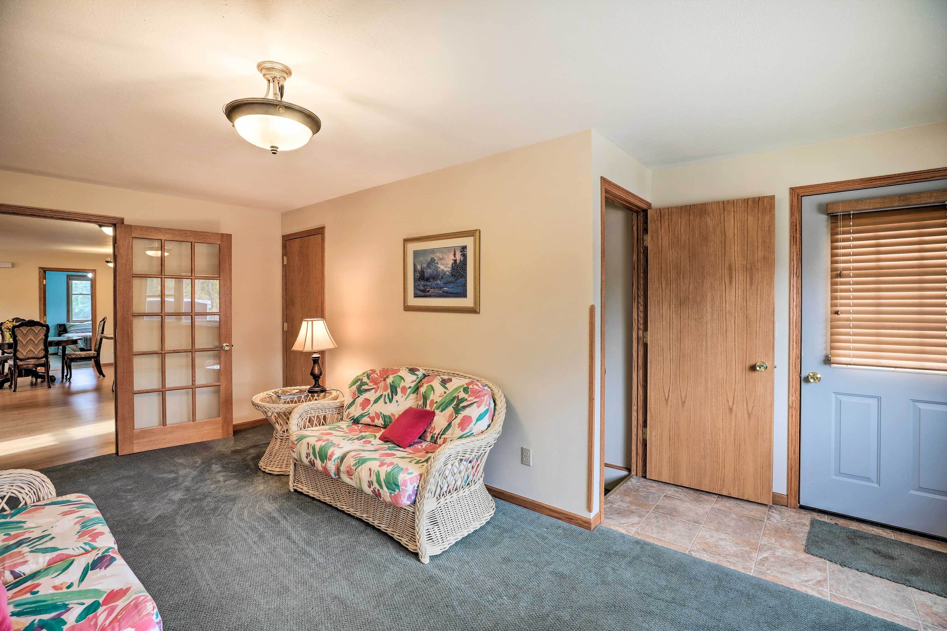 A room with a wicker sofa, a lamp, a framed picture on the wall, and a door with a window.