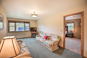 A living room with a sofa, a lamp, a ceiling fan, and a view through a window. - 'eagles View' w/ Game Room - Walk to River! (Crofton)