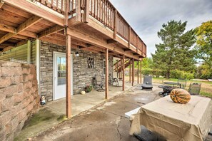 A covered patio area with a stone wall, outdoor seating, and a large pumpkin on a table. - 'eagles View' w/ Game Room - Walk to River! (Crofton)