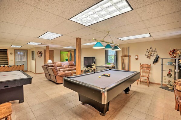 A pool table with a foosball table and a recliner in a well-lit room with a television and decorative items. - 'eagles View' w/ Game Room - Walk to River! (Crofton)