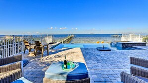 Una terrazza con mobili in vimini, una piccola piscina e vista sul mare.
