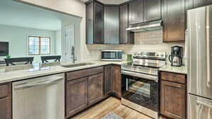 A modern kitchen with dark cabinetry, stainless steel appliances, and a large window. - Waterfront Retreat < 4 Mi to Dtwn Cambridge! (Cambridge)