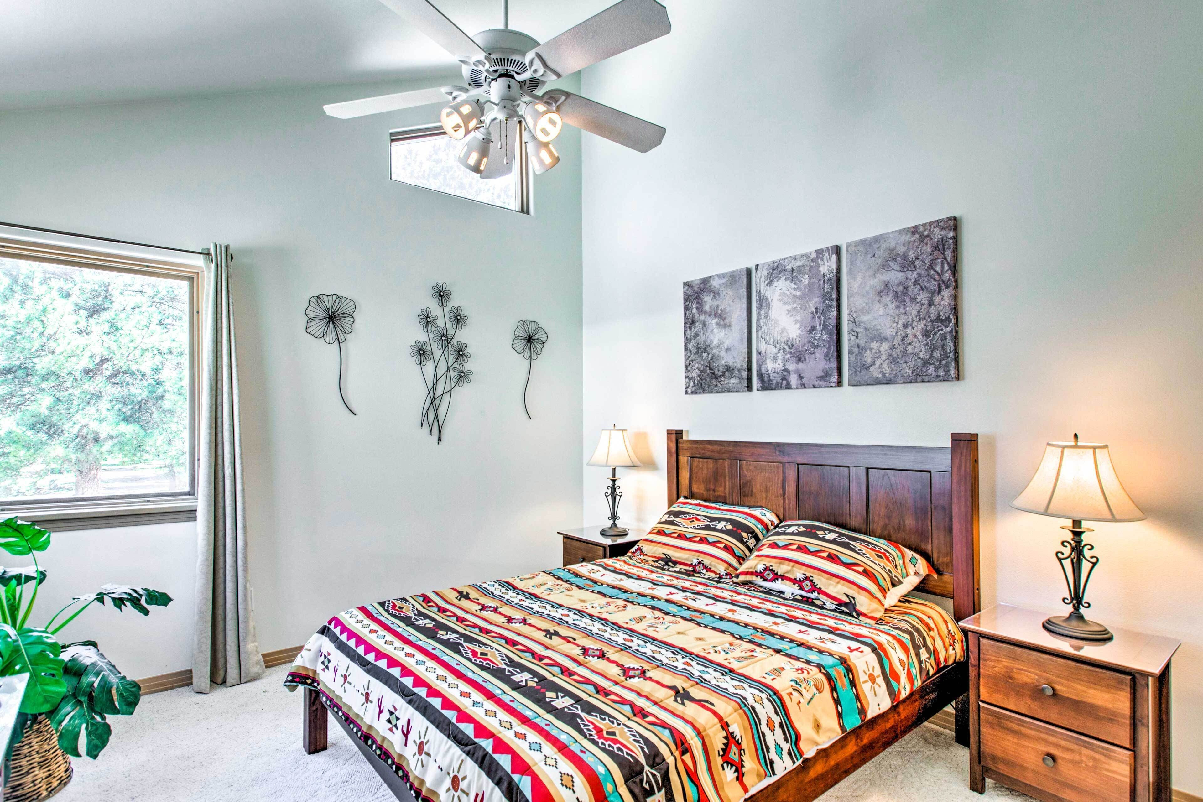 A bedroom with a bed, bedside tables, a ceiling fan, and artwork on the wall.
