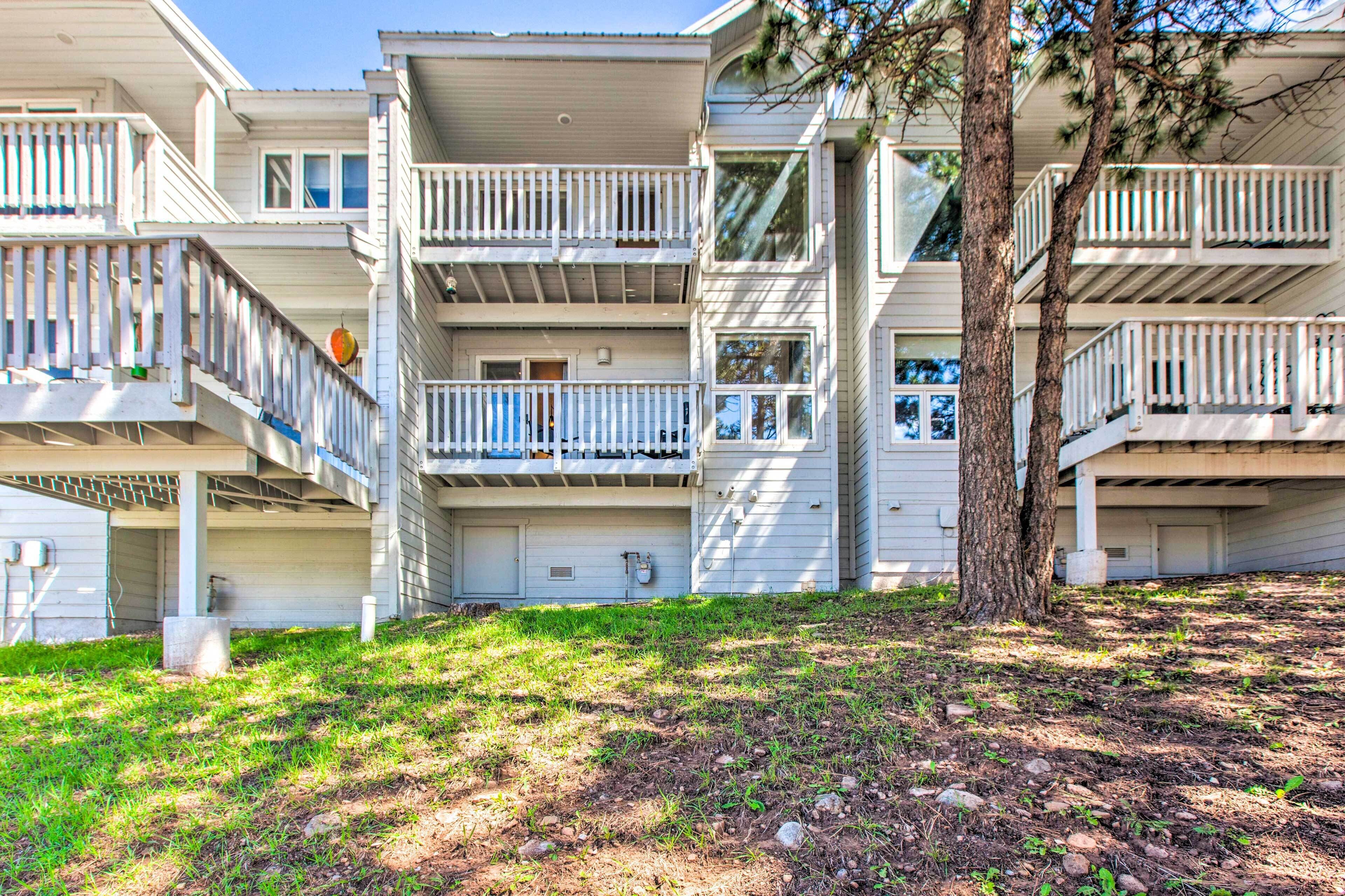 A multi-story residential building with balconies and a tree in the foreground.