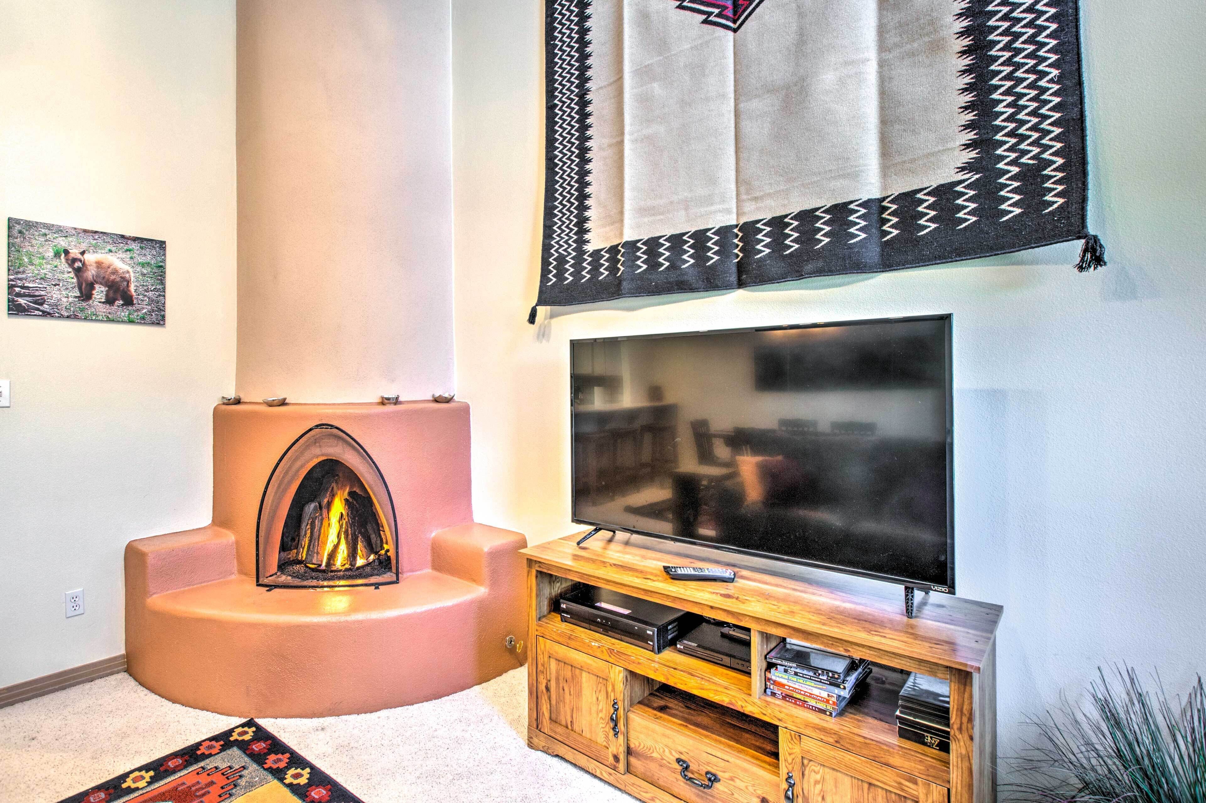 A living room with a fireplace, a flat-screen TV, and a wooden entertainment center.
