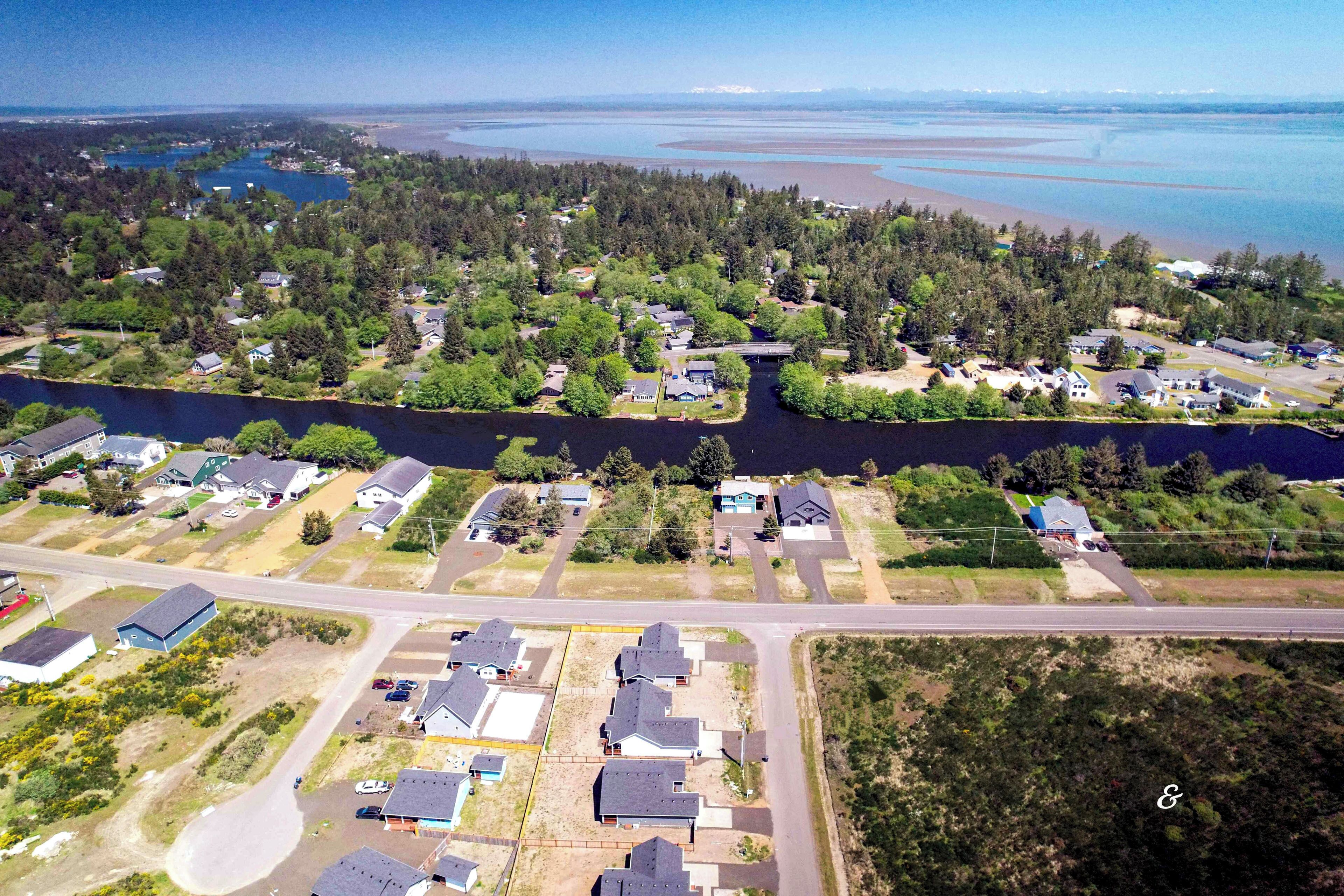 An aerial view of a residential area with houses, a road, and a body of water.