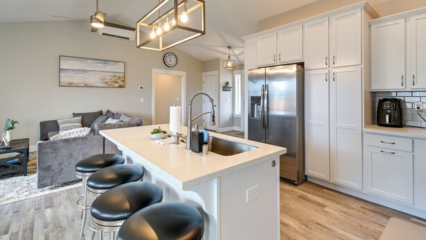 Una cocina moderna con una isla central, electrodomésticos de acero inoxidable y muebles de cocina blancos.