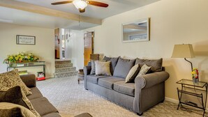 A living room with a grey sofa, a coffee table, a ceiling fan, and a staircase leading to another level. - Jacksonville Getaway ~ 4 Mi to Downtown! (Jacksonville)