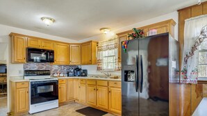 A kitchen with wooden cabinets, a stainless steel refrigerator, a microwave, and a stove. - Jacksonville Getaway ~ 4 Mi to Downtown! (Jacksonville)