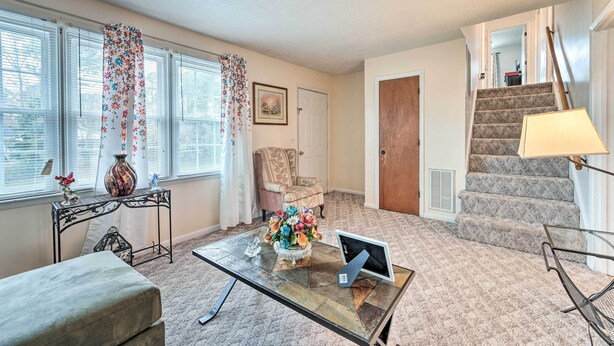 A living room with a glass coffee table, a sofa, a chair, a staircase, and a door. - Jacksonville Getaway ~ 4 Mi to Downtown! (Jacksonville)