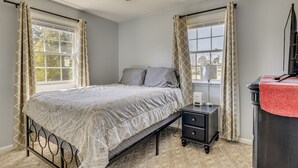 A bedroom with a bed, bedside table, lamp, and curtains. - Jacksonville Getaway ~ 4 Mi to Downtown! (Jacksonville)