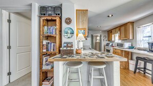 A kitchen with a central island, bar stools, wooden cabinets, a microwave, and a sink. - Ruidoso Cabin w/ Decks ~ 1 Mi to Downtown! (Ruidoso)