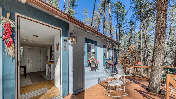 A wooden deck with rocking chairs and a door leading to an interior space. - Ruidoso Cabin w/ Decks ~ 1 Mi to Downtown! (Ruidoso)