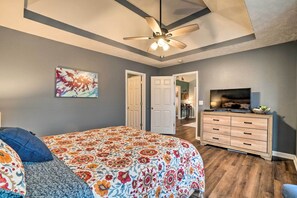 Quarto com cama, ventoinha no teto, cômoda e televisão.
