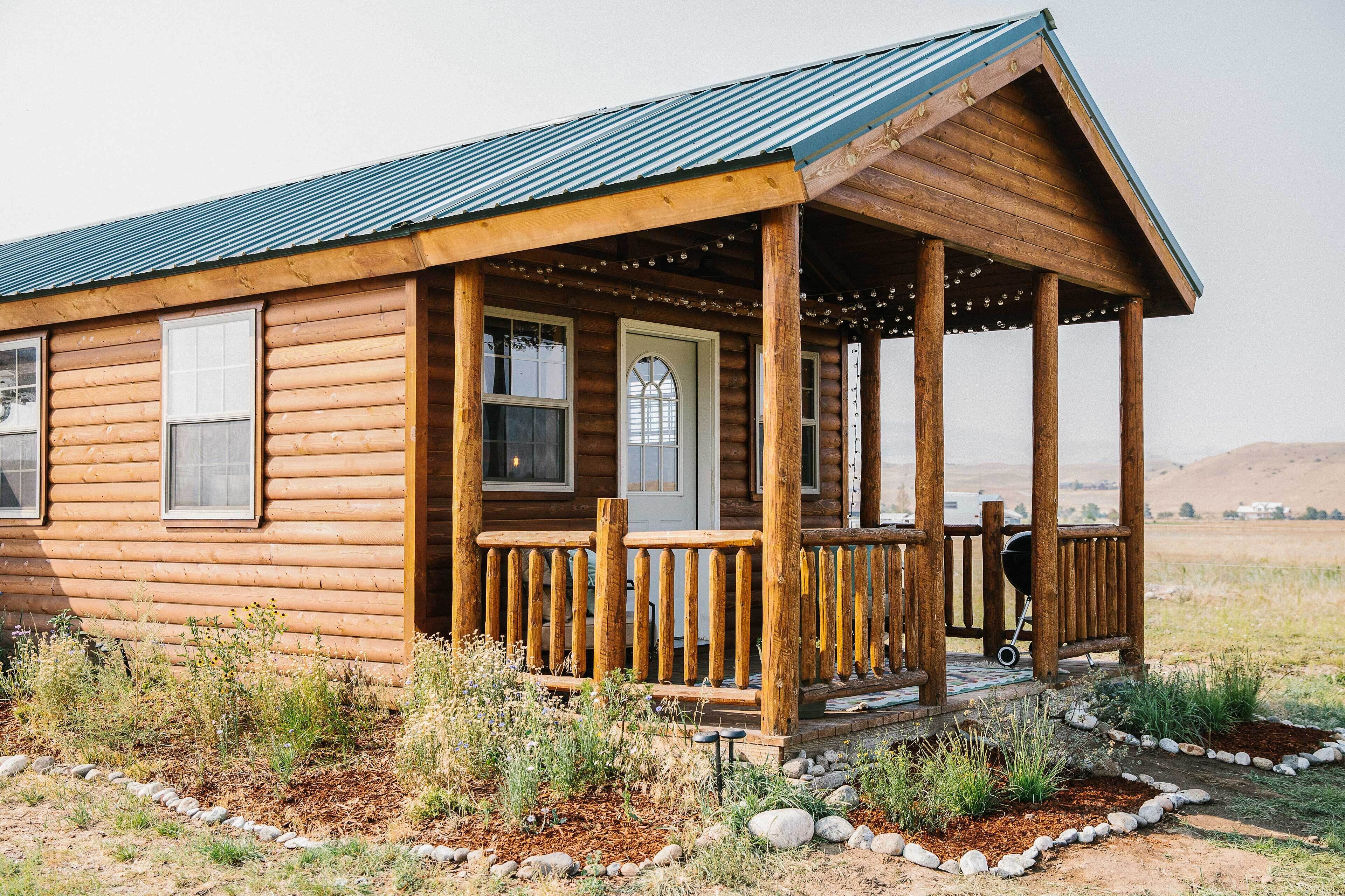 A log cabin with a porch, a door, and a window.