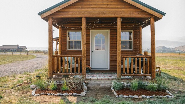 A wooden cabin with a porch, a door, and a small garden area with rocks and plants. - Paradise Valley Cabin by Chico & Yellowstone Park! (Livingston)