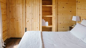 A wooden room with a bed, a wardrobe, and a shelf with folded towels. - Paradise Valley Cabin by Chico & Yellowstone Park! (Livingston)