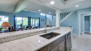 A modern kitchen with a large island, built-in cabinets, and a view to the living area.