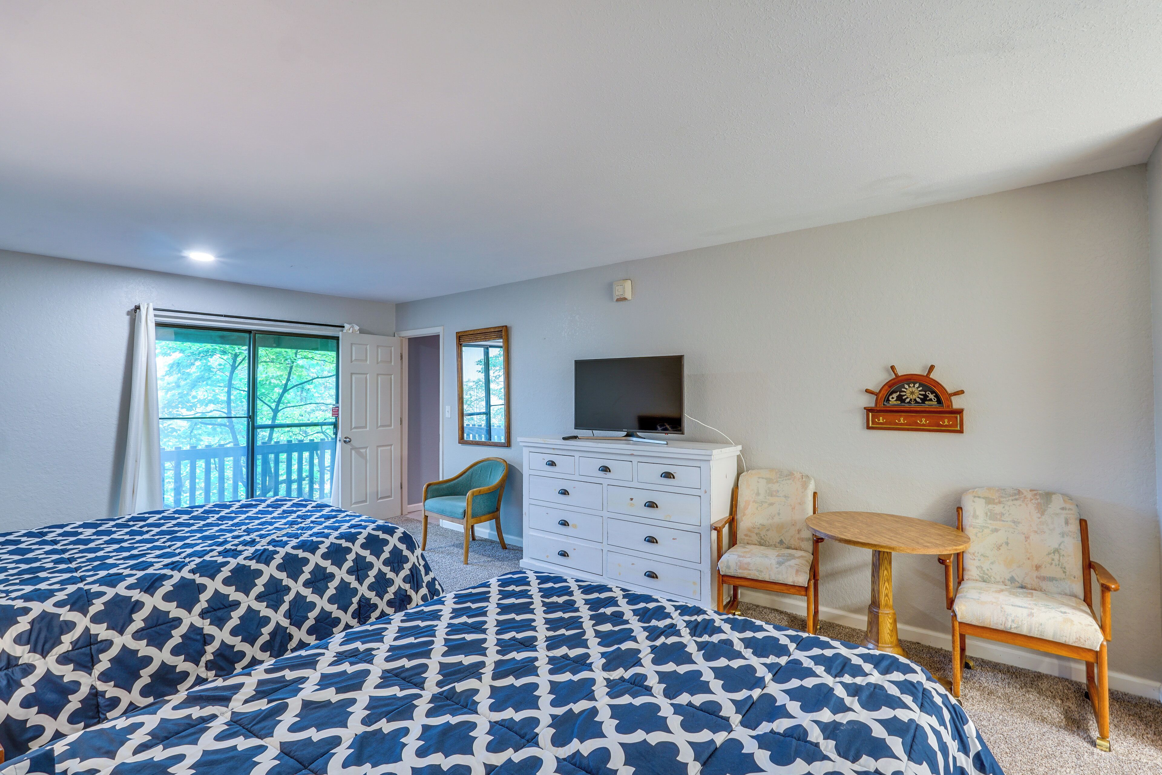 A bedroom with two beds, a dresser, a television, and a small table.