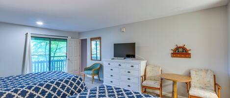 A bedroom with two beds, a dresser, a television, and a small table.
