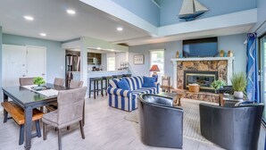 A spacious living area with a dining table, sofas, and a fireplace.
