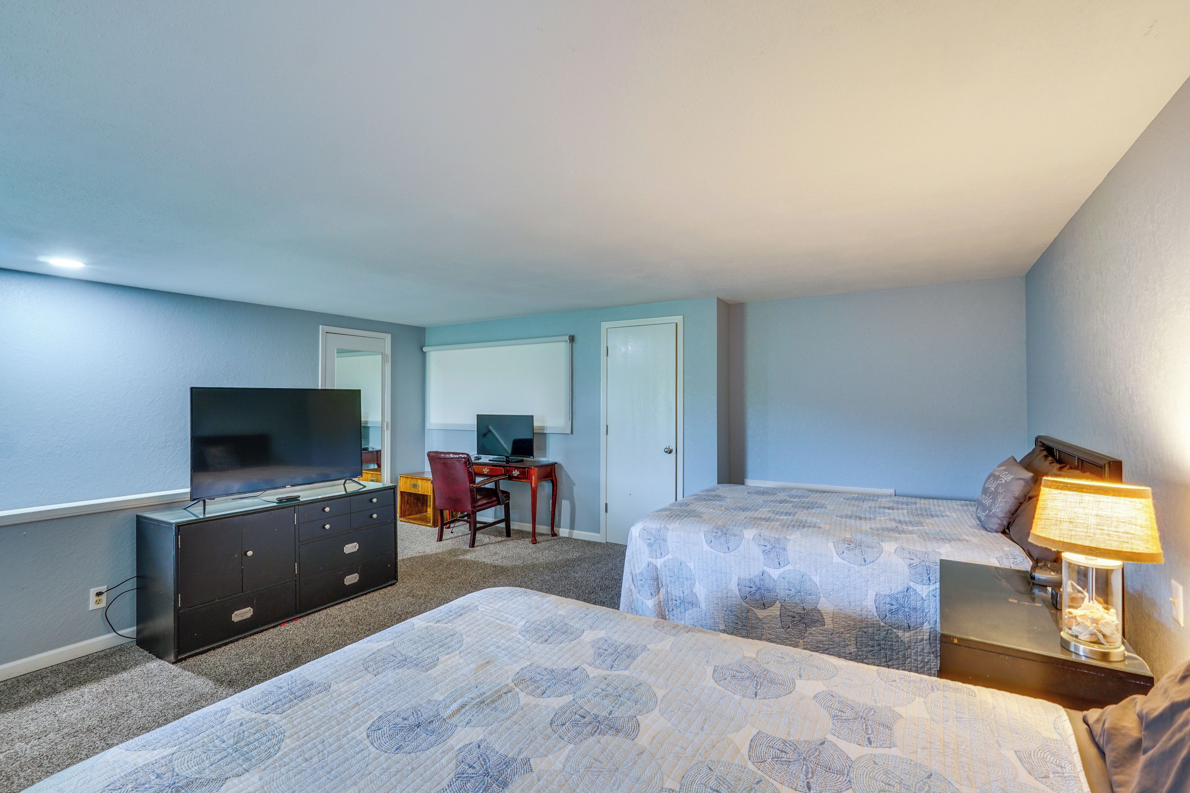 A hotel room with two beds, a desk with a computer, a television, and a lamp.