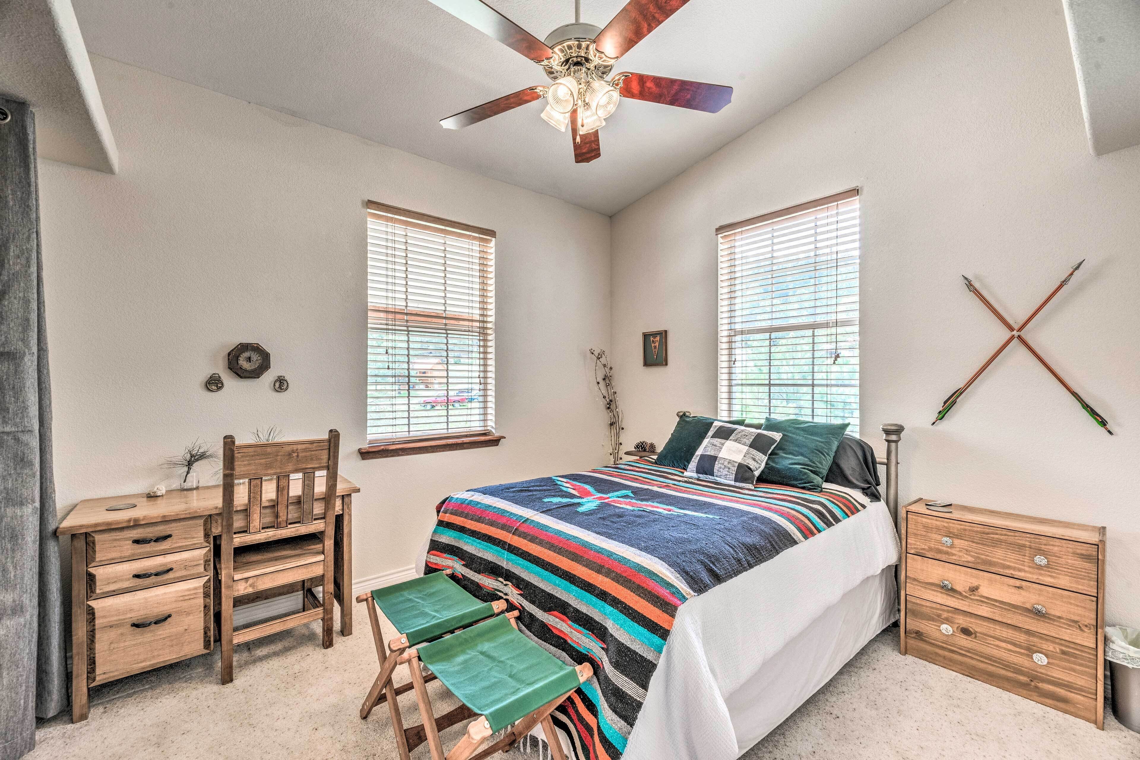 A bedroom with a bed, a desk, a chair, and a dresser.