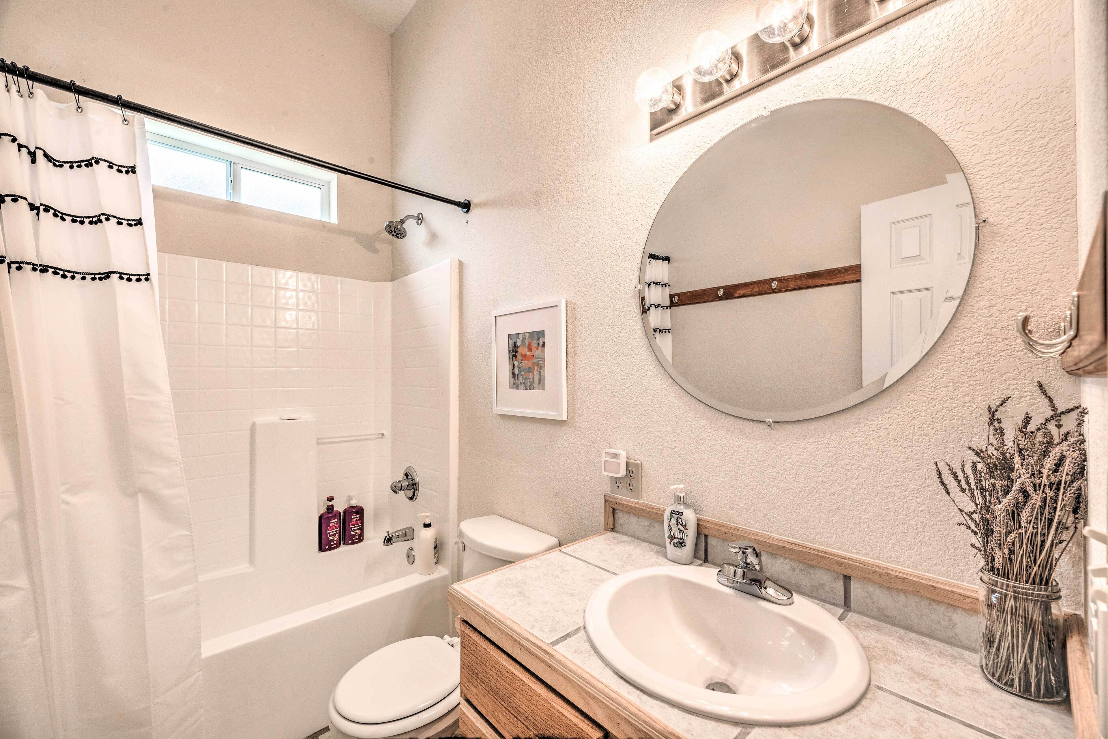 A bathroom with a bathtub, toilet, sink, and a large mirror.