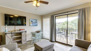 Una sala de estar con televisor, una mesa de comedor y un balcón con vista a la playa.