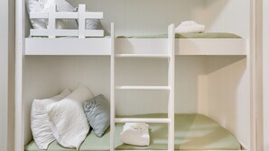 Habitación con literas, barandillas blancas y ropa de cama verde.