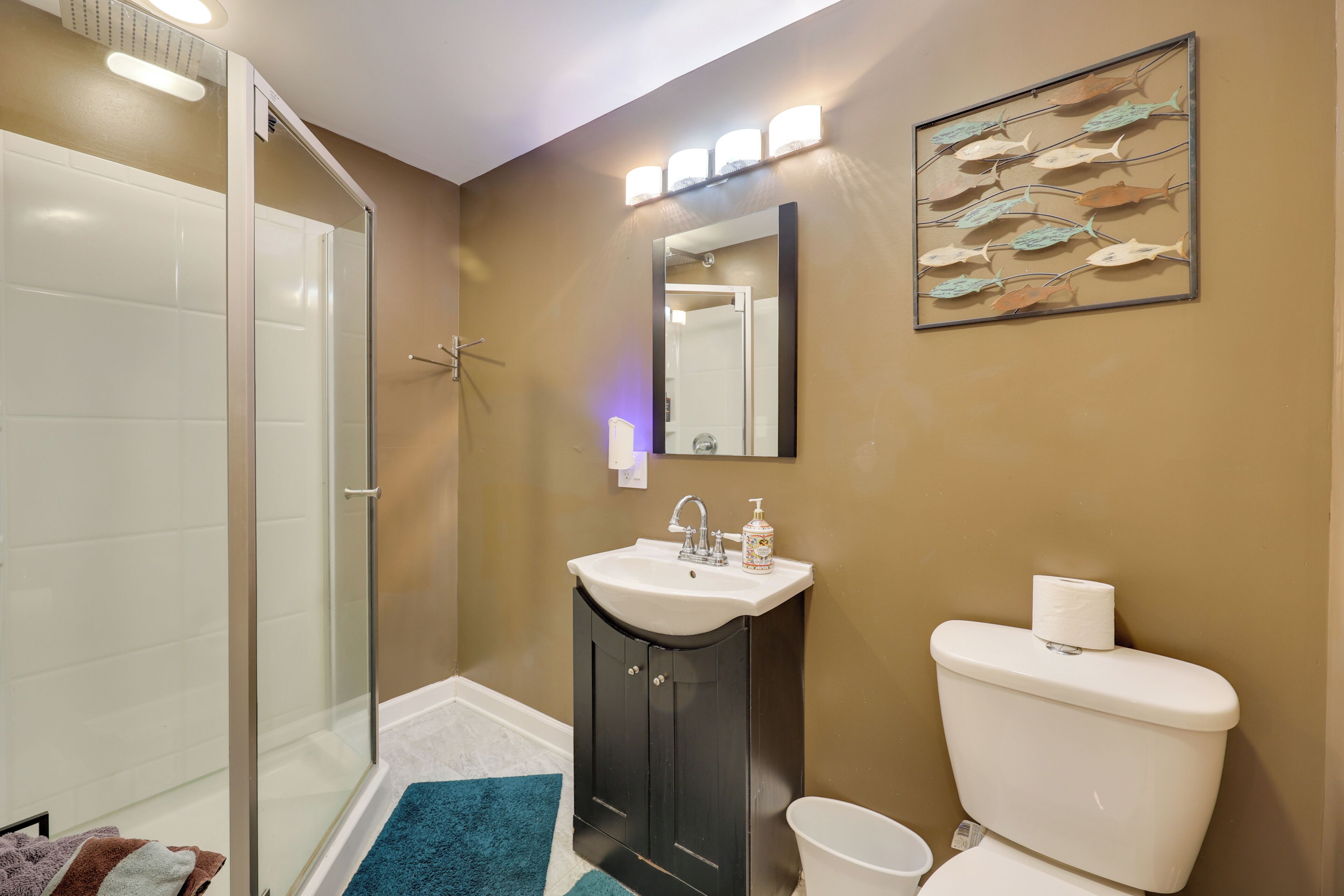 A bathroom with a glass shower enclosure, a sink with a mirror above it, and a toilet.