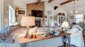 A cozy living room with a fireplace, a television, and a dining area with a table and chairs. - Nantahala Lake Family Home w/ Private Dock & Views (Topton)