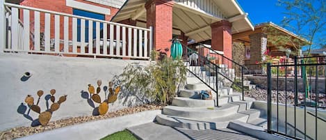 A residential house with a concrete staircase, a white railing, and a cactus mural.