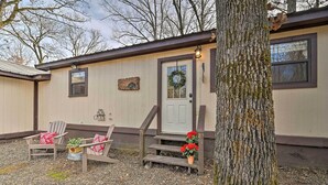 A rustic cabin with a front porch, wooden steps, and two Adirondack chairs with red cushions. - 'hidden Oaks' Broken Bow Vacation Rental, Pets OK! (Broken Bow)