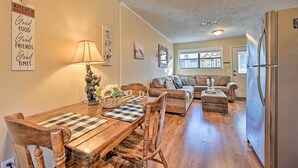 A cozy living room with a wooden dining table, chairs, a sofa, and a refrigerator. - 'hidden Oaks' Broken Bow Vacation Rental, Pets OK! (Broken Bow)