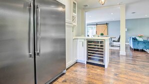 Et moderne køkken med et rustfrit stål køleskab, hvide skabe og en indbygget ovn.