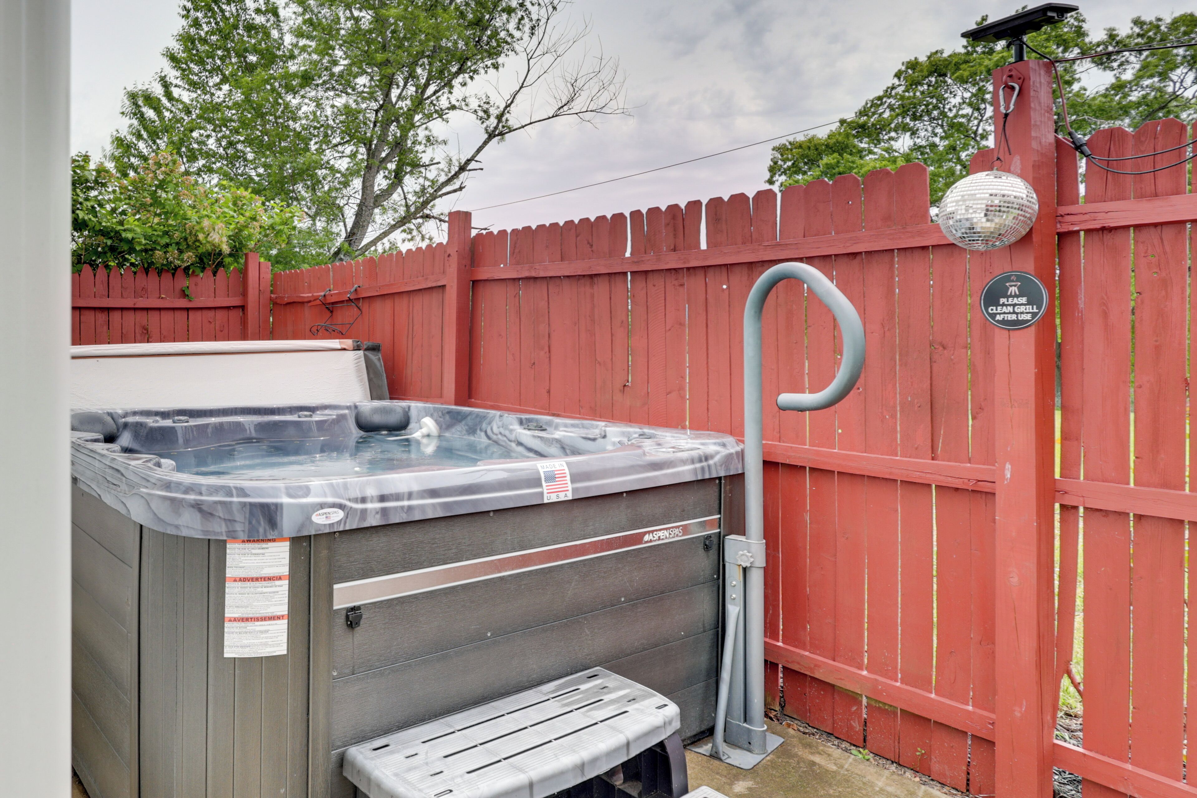 A hot tub with a built-in bench, a red fence, and a disco ball.