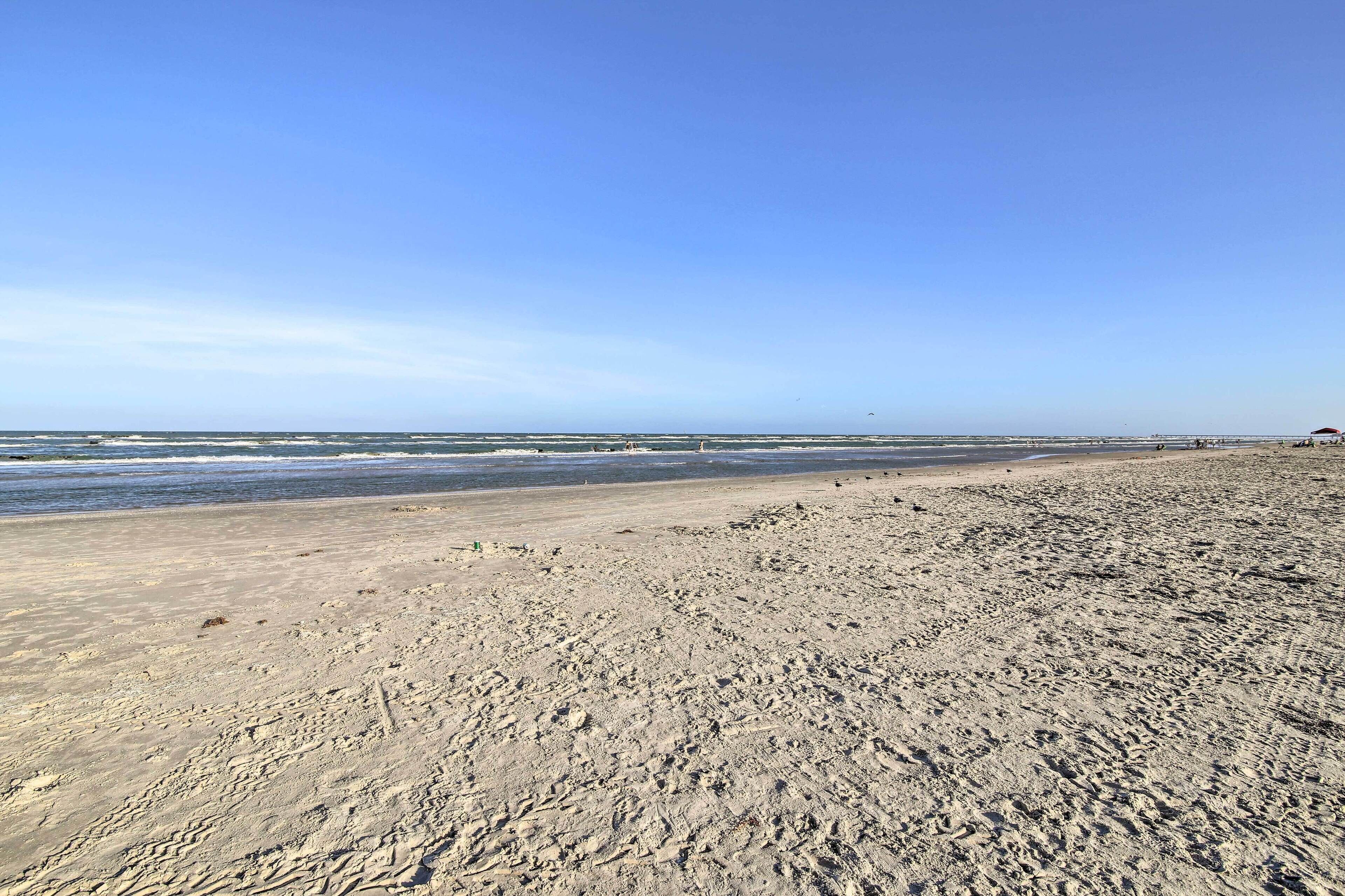 A wide sandy beach with gentle waves and a clear sky.