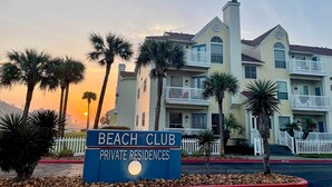 A multi-story building with balconies and a sign reading "Beach Club Private Residences".