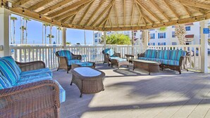 A covered outdoor seating area with wicker furniture and a wooden ceiling.