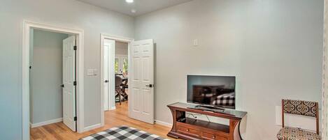 A room with a ceiling fan, a television on a wooden stand, a patterned rug, and a chair.