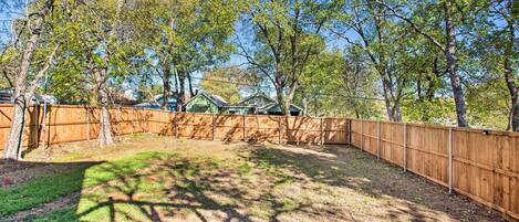 A fenced backyard with trees and a wooden fence.
