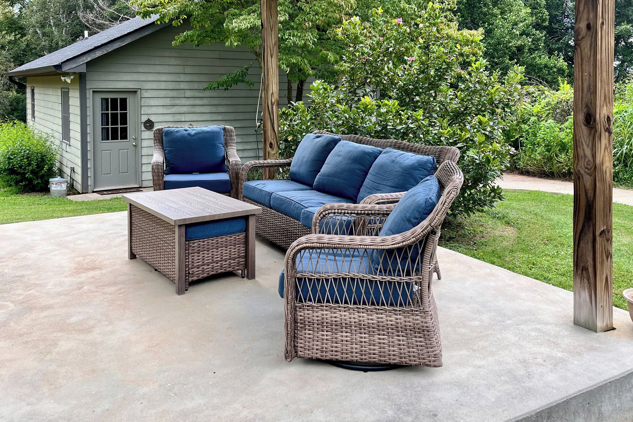 A patio with wicker furniture, including a sofa and chairs, and a small table.