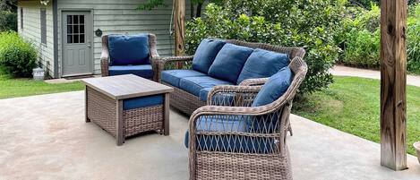 A patio with wicker furniture, including a sofa and chairs, and a small table.