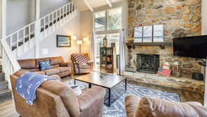 A spacious living room with a stone fireplace, a comfortable seating area, and a staircase leading to an upper level. - Dock, Boat Slip & View: Lakefront Tan-tar-a Home! (Osage Beach)