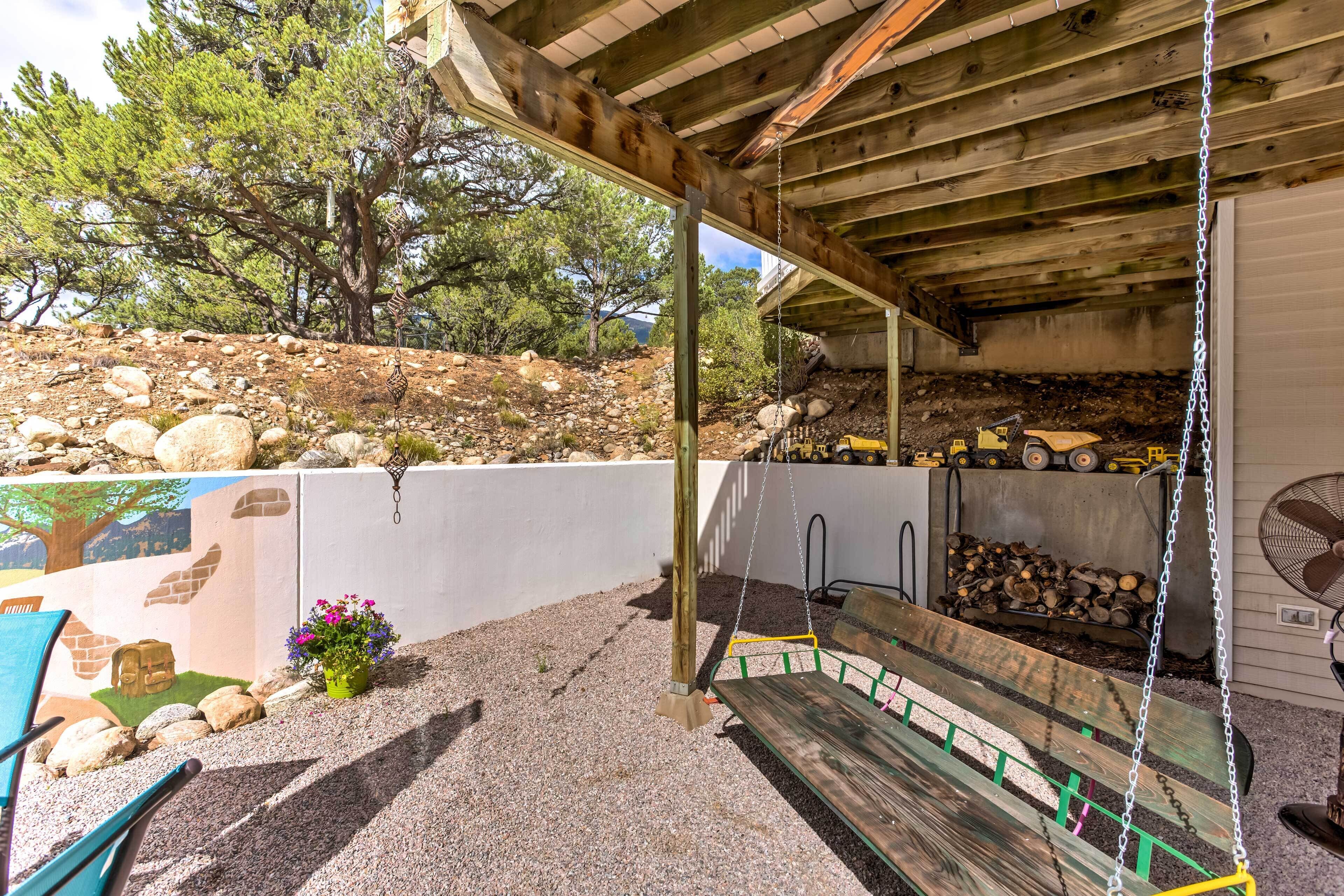 A covered outdoor area with a wooden bench, a swing, and a fan.