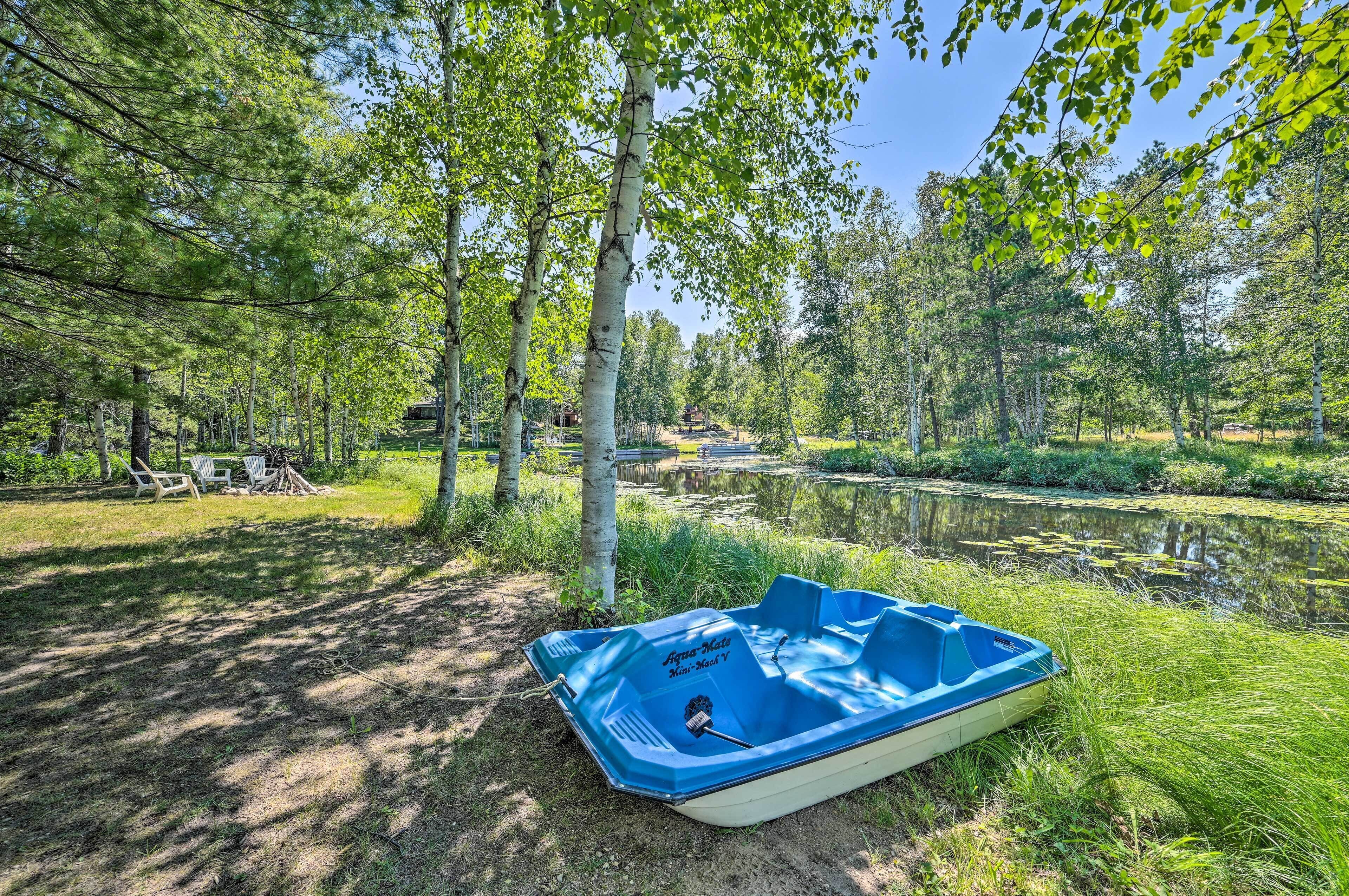 A lakeside campsite with a blue boat, trees, and a clear sky.