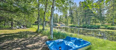 A lakeside campsite with a blue boat, trees, and a clear sky.