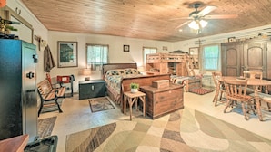 A cozy cabin interior with a wooden ceiling, a bed with a checkered blanket, a dining table with chairs, and a small wooden desk. - Private Murray Abode w/ Fire Pit: Hunt & Fish (Murray)