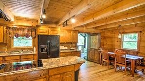 Ein Holzblockhaus-Interieur mit Küche, Essbereich und einem großen Fenster.